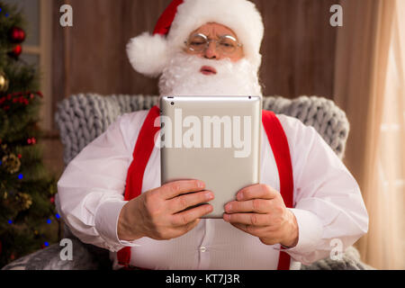 Santa Claus using digital tablet Stock Photo