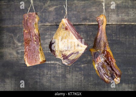 Smoked Meat Hanging on the Rope Against Wooden Background Stock Photo