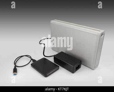 A comparison between hard-drive computer technology within 10 years showing one large hard metal case and one small plastic case Stock Photo