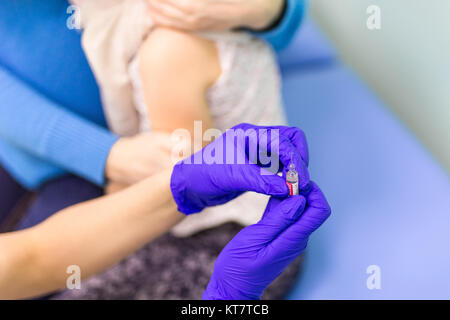 Doctors hand in ultraviolet gloves holding syringe before kids vaccination  against flue. Stock Photo