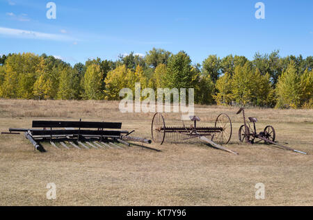 Old farm machinery including a rusty antique cultivator in a field at the Bar U Ranch National Historic Site, Alberta, Canada Stock Photo