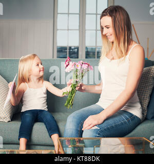 Happy Woman and Child Girl with Flowers at Home. Loving Daughter and Mother Stock Photo