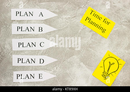 Paper arrows with plan words, time fro planning inscription and a light bulb image on a light concrete background. Business and motivation concept. Sp Stock Photo