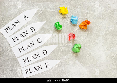 Paper arrows with plan words and colored balls of crumpled paper on a light concrete background. Business and motivation concept. Space for your text  Stock Photo