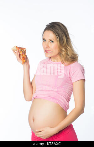 Pregnant woman feeling guilty for eating pizza against a white background Stock Photo