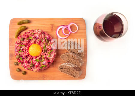 Steak tartare with garnish, wine, and place for text on white Stock Photo