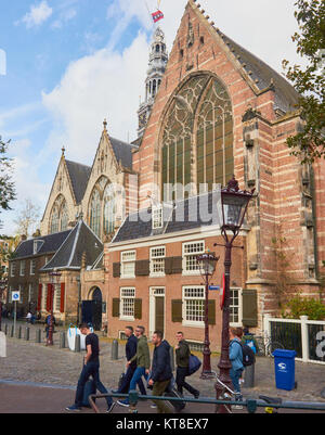 Tourists, Oude Kerk (old church), Ouderkerksplein, Amsterdam, Netherlands. Amsterdam's oldest building founded in 1213 and consecrated in 1306. Stock Photo