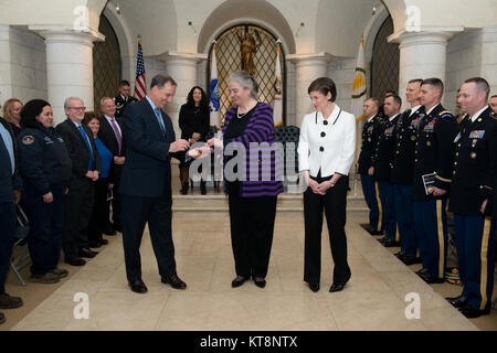 From the left, Gerald B. O’Keefe, administrative assistant to the Secretary of the Army, gives an Senior Executive Service pin to Kathryn Condon, former executive director of Army National Military Cemeteries, to place on Katharine Kelley, superintendent, Arlington National Cemetery, during Kelley’s SES induction ceremony, March 2, 2017, in Arlington, Va. The ceremony took place in the lower level of the Memorial Amphitheater in the cemetery. (U.S. Army photo by Rachel Larue/Arlington National Cemetery/released) Stock Photo
