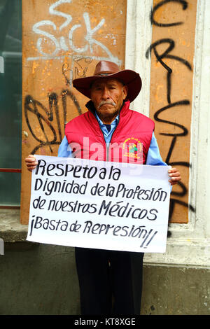 La Paz, Bolivia. 22nd Dec, 2017. A victim of Bolivia's military dictatorships of the 1970s and 1980s holds a placard demanding that the government shows respect for members of the medical profession during a protest outside the Ministry of Justice building. Health service workers in Bolivia have been on strike for 30 days over laws in the new Penal Code that they say allow excessive sanctions for medical negligence and effectively criminalise their profession. Credit: James Brunker / Alamy Live News Stock Photo