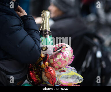 A trader selling balloons, including one shaped like a sparkling wine bottle, on the Zeil shopping street in Frankfurt am Main, Germany, 23 December 2017. Photo: Frank Rumpenhorst/dpa Stock Photo