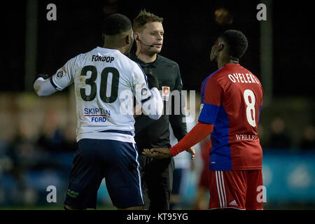 Guiseley, UK. 23rd Dec, 2017. Andrew Miller (Referee) is confronted by Mike Fondop (Guiseley AFC) and Emmanuel Oyeleke (Aldershot Town) after the two were involved in a tackle during Guiseley AFC v Aldershot Town in the Vanarama National League game on Saturday 23 December 2017 at Nethermoor Park, Guiseley, West Yorkshire. Photo by Mark P Doherty. Credit: Caught Light Photography Limited/Alamy Live News Stock Photo