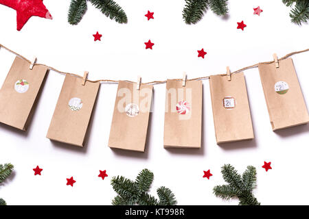 Handmade tinkered advent calendar with paper bags and stickers with fir branches and red stars on a white background Stock Photo