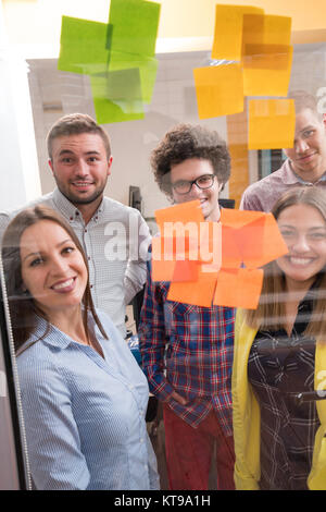 young creative startup business people on meeting at modern office making plans and projects with post stickers on glass Stock Photo