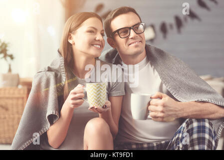 We can travel somewhere. Graceful inspired relaxed couple enjoying the morning together and thinking about their time while sipping morning coffee Stock Photo
