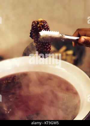 purple waxy corns are boiled in the basin Stock Photo