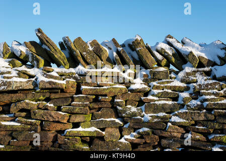 Close up of a traditional drystone wall covered in snow in the High Peak, Derbyshire, England. Stock Photo