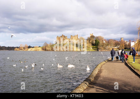 Families enjoying spells of sunny weather beside Linlithgow Loch at Linlithgow Palace in Scotland, United Kingdom Stock Photo