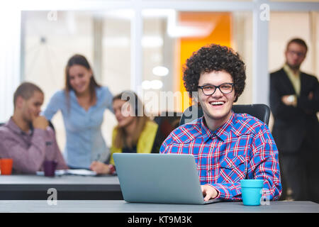 Portrait of startup group of creative people having a meeting with a laptop in a modern office. Business people having relaxed conversation over new p Stock Photo