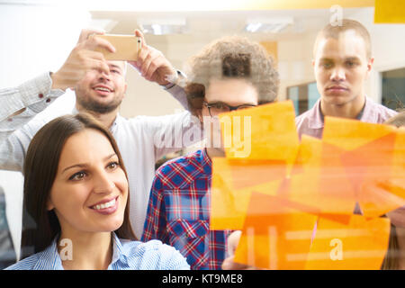 young creative startup business people on meeting at modern office making plans and projects with post stickers on glass Stock Photo