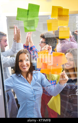 young creative startup business people on meeting at modern office making plans and projects with post stickers on glass Stock Photo