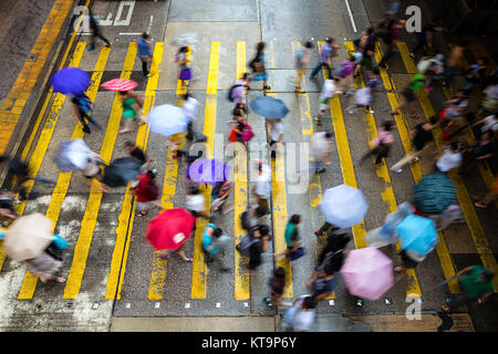 Motion blurred pedestrians crossing Hong Kong street in the rain Stock Photo