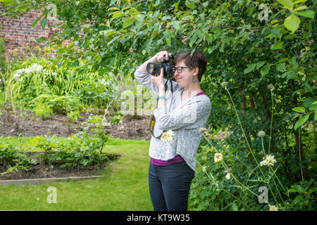 Young female photographer takes photos in garden, Richmond, Yorkshire, England Stock Photo