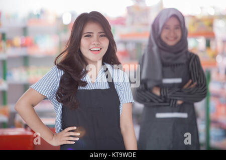 excited asian female shopkeeper standing in front of the store Stock Photo