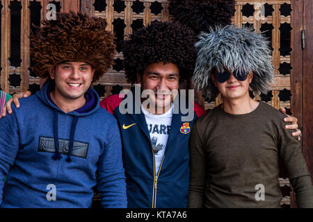 Young Uzbek Men Trying On Traditional Hats, The Registan, Samarkand, Uzbekistan Stock Photo