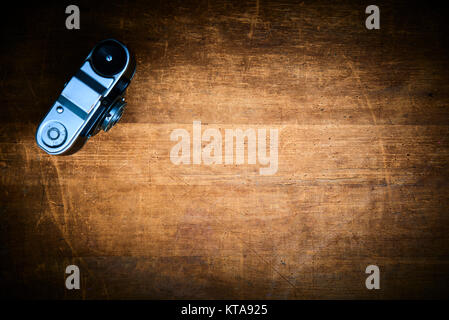 Vintage photo film camera with group of  slides on a scratched old wooden table. Stock Photo