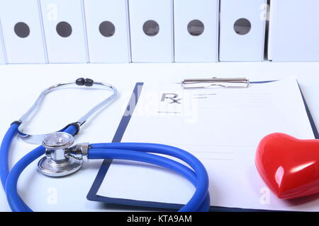 Closeup of medical stethoscope on a rx prescription, red heart isolated on white background.