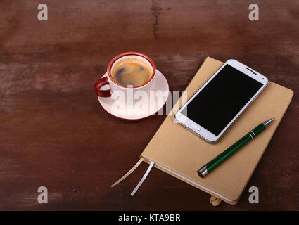 Empty notebook and ball pen with a cup of coffee, phone of the office desk. Business concept . Stock Photo
