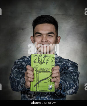 PORTLAND, Ore. (Dec 5, 2017) – Personnel Specialist 2nd Class John Paul T. Delossantos, the submarine tender USS Frank Cable's (AS 40) Junior Sailor of the Year, from Manila, Republic of the Philippines, holds up his secret weapon to prioritizing and balancing his work flow, Dec. 5. Frank Cable is currently completing a dry-dock phase maintenance availability. The ship will get underway soon for sea trials, which constitutes the final determination of a ship’s ability to re-join the fleet as an operational unit to conduct maintenance and support submarines and surface vessels deployed to the I Stock Photo