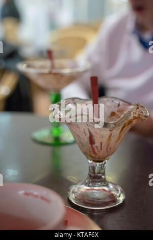 Two empty sorbet glasses on a table with a person sitting in the background Stock Photo