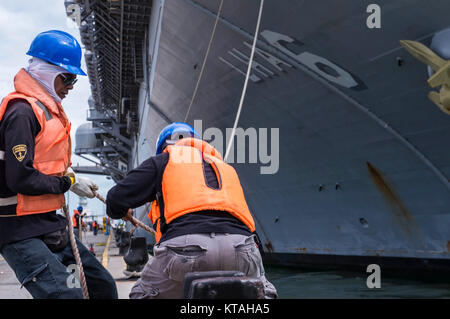 Singapore (Dec. 22, 2017) - Singaporean contractors moor the amphibious assault ship USS America (LHA 6) as she pulls in to RSS Singapura - Changi Naval Base, Singapore during a regularly scheduled port visit Dec. 22. America, part of the America Amphibious Ready Group, with embarked 15th Marine Expeditionary Unit, is operating in the Indo-Asia Pacific region to strengthen partnerships and serve as a ready-response force for any type of contingency. (U.S. Navy Stock Photo