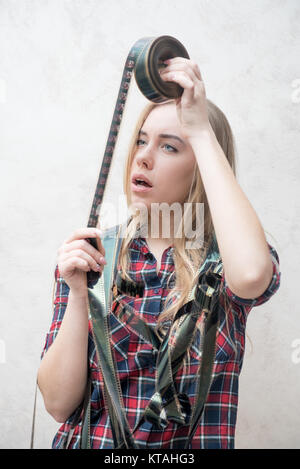 Portrait of attractive blonde woman with movie film reel unrolled, looking at transparent frames Stock Photo