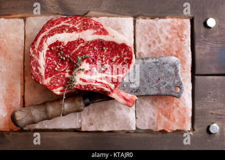 Bone In Rib Eye row Steak on pieces of salt Stock Photo