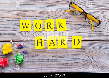 Work hard printed inscription, glasses and balls of crumpled paper on a light wooden background, top view.Light wooden background. Business and motiva Stock Photo