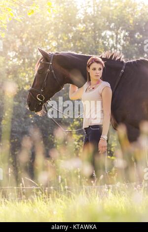 wonderful young equestrian woman with horse in summer sun nature Stock Photo
