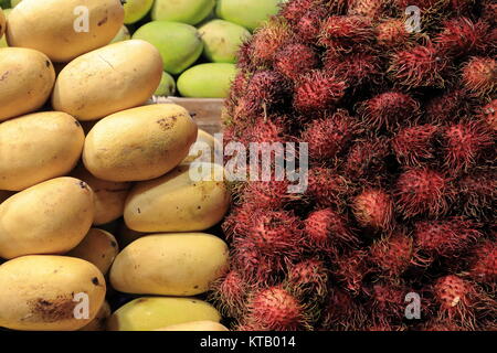 Rambutan-yellow and green mango fruits piled together-stall on the ground floor fronting the sidewalk of Leveniza Street-outer side San Andres Market. Stock Photo