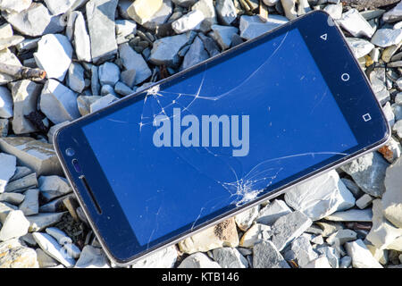 Frustrated phone on the rocks. Glass shattered on rocks on a sma Stock Photo