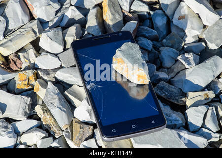 Frustrated phone on the rocks. Glass shattered on rocks on a sma Stock Photo