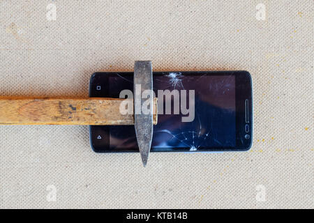 Hammer and smartphone. The screen of the smartphone, a broken ha Stock Photo