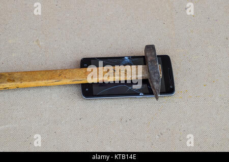 Hammer and smartphone. The screen of the smartphone, a broken ha Stock Photo