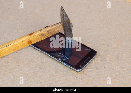 Hammer and smartphone. The screen of the smartphone, a broken ha Stock Photo