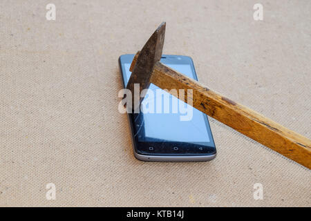Hammer and smartphone. The screen of the smartphone, a broken ha Stock Photo