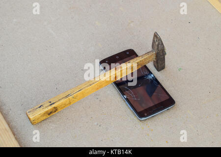 Hammer and smartphone. The screen of the smartphone, a broken ha Stock Photo