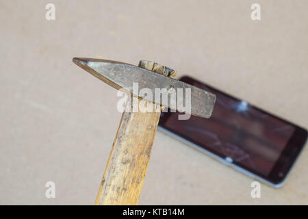 Hammer and smartphone. The screen of the smartphone, a broken ha Stock Photo