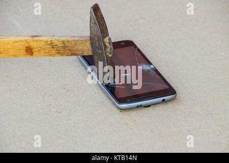 Hammer and smartphone. The screen of the smartphone, a broken ha Stock Photo