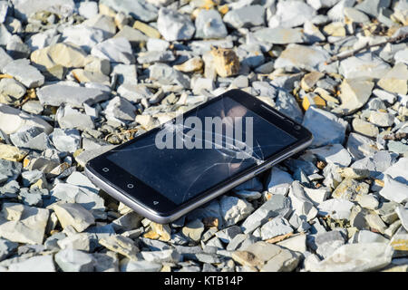 Frustrated phone on the rocks. Glass shattered on rocks on a sma Stock Photo