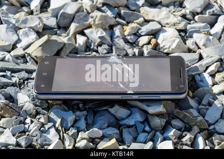 Frustrated phone on the rocks. Glass shattered on rocks on a sma Stock Photo